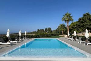 a swimming pool with chairs and umbrellas at Agriturismo Tenute Mauro in Ispica