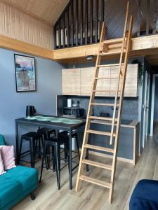 a loft bed in a tiny house with a table and chairs at Ostoja Radków całoroczny domek z balią in Wünschelburg