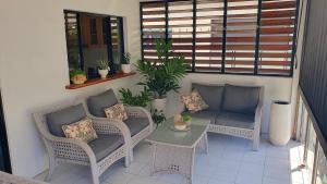 a balcony with wicker chairs and a table and a couch at Palmview Escape in Yorkeys Knob