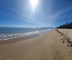 a sandy beach with the ocean on a sunny day at Palmview Escape in Yorkeys Knob +20 photos
