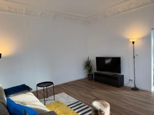 a living room with a couch and a flat screen tv at StaySimplyHaven - Modernes City-Apartment, King-Size Bett, 55'' Smart-TV, Self Check-In in Braunschweig