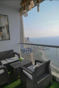 balcone con sedie, tavoli e vista sull'oceano di شقة في برج داماك a Gedda