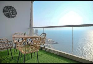 un balcone con tavolo e sedie e l'oceano di شقة في برج داماك a Gedda Altre 4 foto