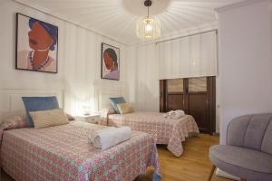 a room with two beds and a chair in it at Castillo Buenavista in Ponferrada