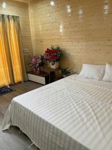 ein großes weißes Bett in einem Zimmer mit Blumen in der Unterkunft Tamcoc Athletic Bungalow & Restaurant in Ninh Bình