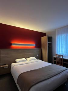 a bedroom with a large bed with a red wall at Fasthotel Laval in Laval
