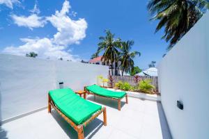 due panchine verdi sedute su un patio di Ô TALIA Hôtel and SPA a Nungwi