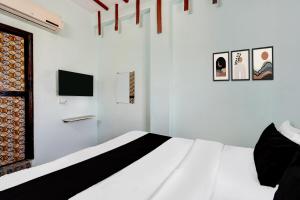 a white bedroom with a bed and a tv at HOTEL O MID STAR in Sakardarā