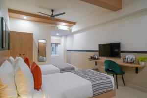 Una habitación de hotel con dos camas, un escritorio y un televisor. en Olive Hotel Hitec City by Embassy Group, en Hyderabad