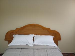 un letto con testiera in legno e 2 cuscini bianchi di ENECO a San Martín