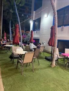 a restaurant with tables and chairs with grass and palm trees at Queens Hostel Waikiki in Honolulu