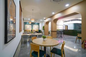 a waiting area with tables and chairs in a building at Olive Hotel Hitec City by Embassy Group in Hyderabad +37 photos