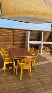 a wooden table and yellow chairs on a deck at El Fortín de los Choros, un descanso para la familia in Los Choros