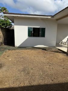 uma casa branca com uma janela num quintal em Casa completa com dois quartos e uma suíte master, localizada no bairro Alphaville Fazendinha em Macapá