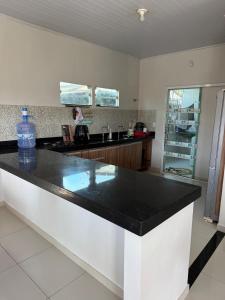 uma grande cozinha com um balcão preto em Casa completa com dois quartos e uma suíte master, localizada no bairro Alphaville Fazendinha em Macapá mais 8 fotografias