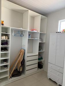 um armário branco com prateleiras brancas e um violão em Casa completa com dois quartos e uma suíte master, localizada no bairro Alphaville Fazendinha em Macapá