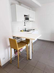a kitchen with a table and a yellow chair at Modern studio Belval in Esch-sur-Alzette