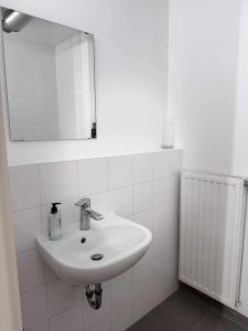a white bathroom with a sink and a mirror at Modern studio Belval in Esch-sur-Alzette