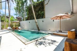 MODERN AND COMFORTABLE JUNGLE VISTA HOTEL Ubud Bali By JV with a relaxing atmosphere في أوبود: مسبح فيه مظله وبعض الكراسي