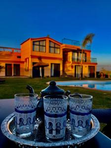 drei blau-weiße Gläser auf einem Tablett mit einem Haus in der Unterkunft Tynass Ferme in Fès