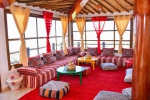 ein Wohnzimmer mit Sofas, Tischen und Fenstern in der Unterkunft Tynass Ferme in Fès