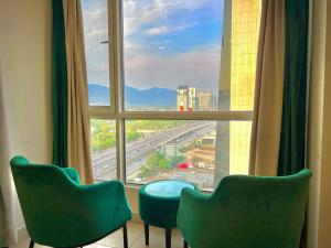 two green chairs sitting in front of a large window at Elysium Tower Luxury Studio & One Bedroom Apartments Opposite Centaurus Mall Islamabad in Islamabad