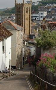 Una calle de la ciudad con una torre de reloj y una iglesia. en The Rest, en St Ives