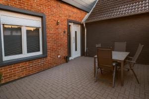 eine Terrasse mit Tisch und Stühlen neben einer Backsteinmauer in der Unterkunft Stadtzentrum Apartment - Modern & Ruhig in Quakenbrück