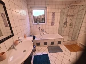 a bathroom with a tub and a sink and a shower at Ferienwohnung Oskar in Gschwend +5 photos