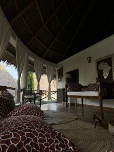 Villa Peponi Royale Watamu في واتامو: غرفة بسرير وكراسي وطاولة