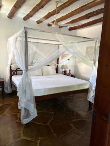 Villa Peponi Royale Watamu في واتامو: غرفة نوم بسرير أبيض مع مظلة
