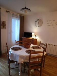 Una habitación con una mesa y sillas y un reloj en la pared. en Laïta - Séjour à Quimperlé, en Quimperlé