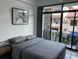 a bedroom with a bed and a window with a horse picture at Hug14 Hotel in Ban Bang Toei (1)