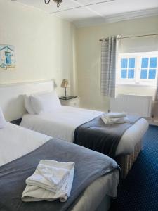una camera d'albergo con due letti con asciugamani sopra di The Ilchester Arms ad Abbotsbury