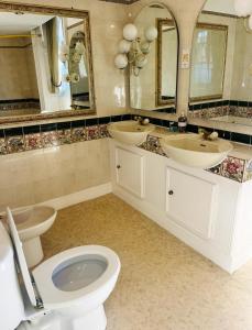 bagno con 2 lavandini, servizi igienici e specchi di The Ilchester Arms ad Abbotsbury