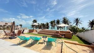 eine Gruppe von Stühlen und Sonnenschirmen auf einer Terrasse in der Unterkunft Vista pro mar maravilhosa,Tibau-RN - INNOVA in Tibau