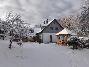 a white house with a gazebo in the snow at Penzion U Ovečky in Jeseník