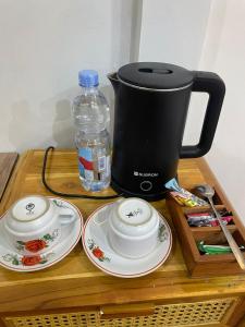 eine Kaffeemaschine, zwei Teller und eine Flasche Wasser in der Unterkunft pojok kahyangan homestay and cabin in Kejajar
