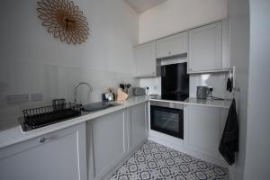 a kitchen with white cabinets and a sink at Island View in Campbeltown