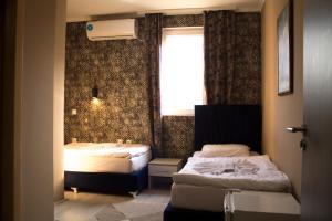two beds in a small room with a window at Hotel In the heart of Old Bazaar with private parking in Skopje