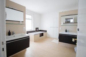 Un baño con dos lavabos, una bañera y un espejo. en Gästezimmer Volksdorf, en Hamburgo
