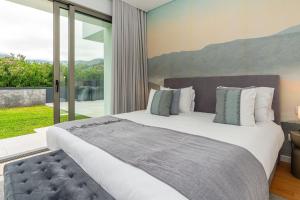 a bedroom with a large bed and a large window at Elysium São Vicente - Designer Villa with Ocean View, Heated Pool, Jacuzzi & Sauna in São Vicente +66 photos