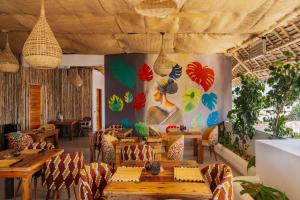 un ristorante con tavoli e sedie e un dipinto sul muro di Ô TALIA Hôtel and SPA a Nungwi