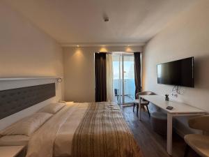 Schlafzimmer mit einem großen Bett, einem Schreibtisch und einem TV in der Unterkunft Alliance palace Black Sea in Batumi