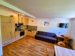 a living room with a blue couch and a kitchen at Oberstockachhof in Schwendau