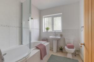 a white bathroom with a tub and a toilet and a sink at Spacious 4 Bed 2 Bath House in Beoley +27 photos