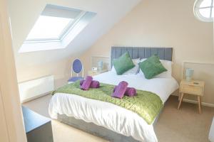 a bedroom with a bed with purple pillows on it at Spacious 4 Bed 2 Bath House in Beoley