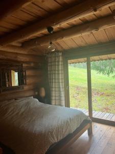 Un dormitorio con una cama y una ventana grande. en Chalet canadien en Morvan, en Rouvray