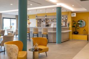 un bar in un ristorante con pareti e sedie gialle di DOMITYS - Galia a Brive-la-Gaillarde