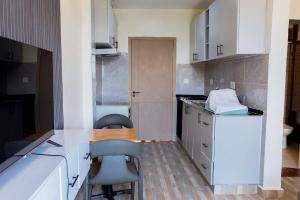 基加利Cozy Studio Retreat的配有白色橱柜、桌子和椅子的厨房